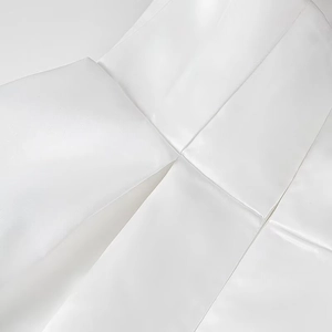 Dettaglio macro del tessuto di raso bianco con pieghe intricate e cuciture raffinate