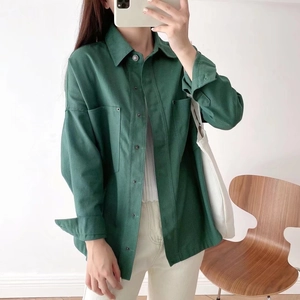 Detailed close-up of a dark green corduroy jacket with front pockets and button closure