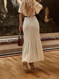 Dettagli del vestito in maglia a pieghe bianco con orlo traforato e cintura nera