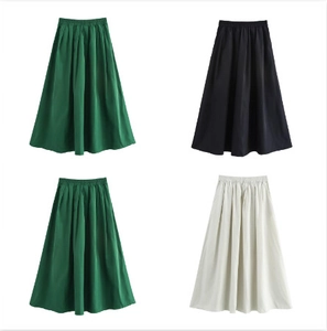 Détail de jupes midi évasées en vert foncé, noir et beige avec une taille élastique