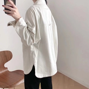 Detail of white denim shirt jacket showing curved side slit hem and reinforced back seam
