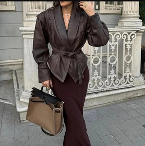 Détail d'une veste vintage en cuir marron foncé avec ceinture et jupe longue