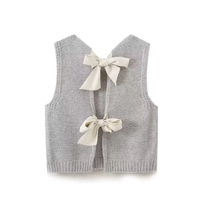 Gilet in maglia grigia da donna con fiocchi bianco crema su sfondo bianco pulito