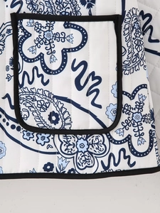 Detail of white quilted fabric with blue paisley print and black woven trim edges