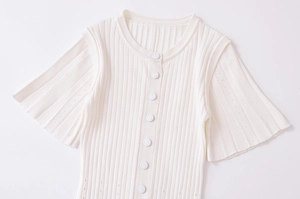 Dettaglio cardigan in maglia a costine bianca con bottoni incisi e tessuto materico