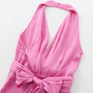 Robe midi en satin rose avec licou et grand nœud décoratif sur fond blanc immaculé