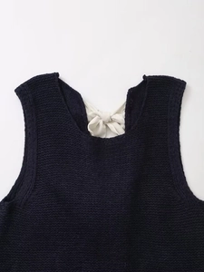 Dettaglio gilet in maglia blu scuro con fiocco color crema e trama a treccia fitta