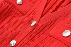 Détail du tissu en maille côtelée rouge avec boutons en métal argenté et couture fine