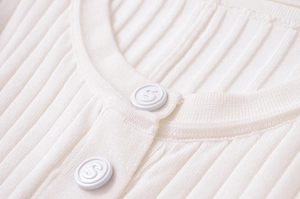 Dettaglio di abito in maglia a coste con scollo rotondo e bottoni avorio con logo S