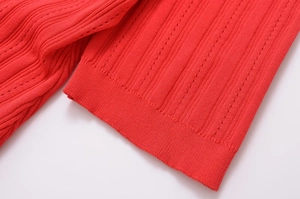 Vue macro d'une robe en maille rouge montrant la texture côtelée et les détails ajourés
