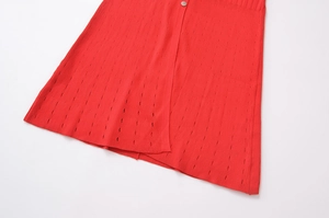 Détail d'une robe en maille rouge avec motifs ajourés et bouton métallique élégant
