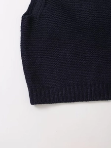 Dettaglio del gilet in maglia blu scuro con trama a punto perla e bordo a costine