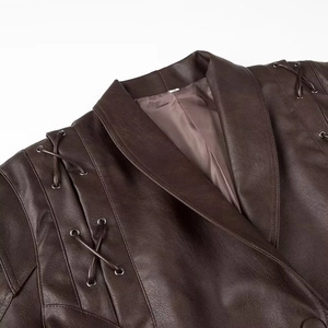 Détail d'une veste en cuir marron foncé avec œillets métalliques et lacets vintage
