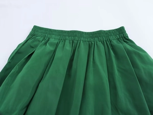 Détail de la jupe midi plissée verte avec une large ceinture élastique à taille haute
