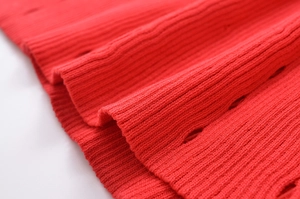 Vue détaillée du tricot rouge avec texture à côtes verticales et motifs ajourés élégants