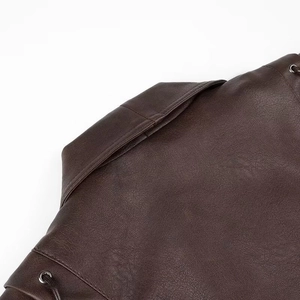 Détail macro du col d'une veste en cuir marron foncé avec œillets et laçage vintage
