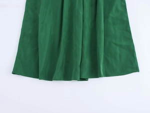 Détail du tissu en satin vert émeraude brillant et de l'ourlet de la jupe midi