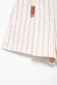 Detail of striped cotton shorts featuring red vertical patterns and a woven belt
