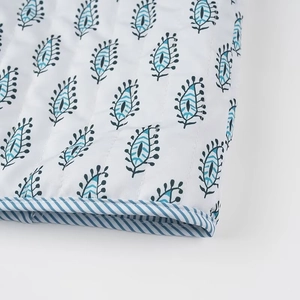 Dettaglio della giacca trapuntata reversibile con stampe a foglie blu e bordo a righe
