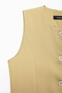 Détail du gilet sans manches kaki montrant les boutons et la texture du tissu en sergé