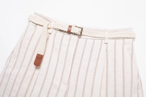 Detailed macro view of cream shorts with red vertical stripes and woven belt detail