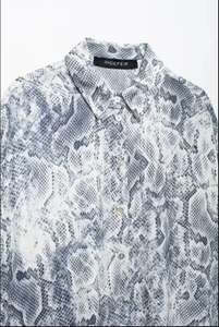 Detail of snake print shirt collar and pearlescent buttons on smooth fabric