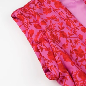 Detailed macro view of pink floral jacquard fabric with elegant red flower patterns
