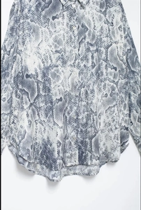 Detailed view of long-sleeve shirt with grey snake print pattern and button-down front