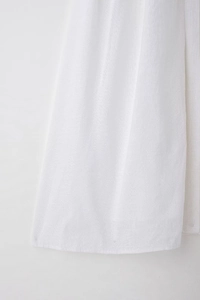 Detailed close-up of premium white linen fabric texture on a summer midi shirt dress