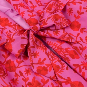 Close-up of rose pink fabric with floral print and a decorative tied bow detail