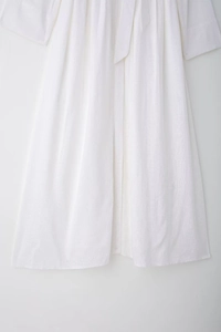 Detail of white cotton linen midi dress showing natural fabric texture and waist tie
