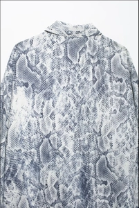Detailed macro view of snake print fabric pattern on women's long sleeve shirt