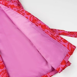 Detailed macro shot of pink satin vest with red floral embroidery and warm lining