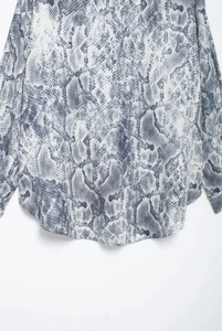 Detail of grey snakeskin print blouse showing fabric texture and curved hemline