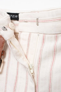 Detail view of striped trousers featuring button closure and a metal hook fastener