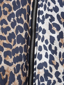 Detailed macro view of the sturdy black zipper on a stylish leopard print jacket fabric