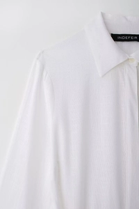 Detailed macro view of white cotton linen shirt collar with professional INDEFEIR brand label