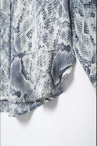 Close-up of snakeskin print shirt showing button detail and smooth curved hemline