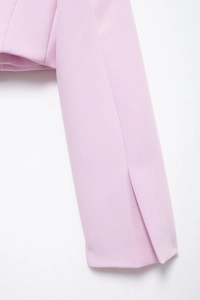 Détail de la manche d'une veste en satin rose clair avec fente latérale et coutures