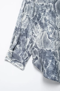 Close-up of snake skin print texture and button cuff detail on the long sleeve shirt