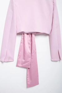 Détail du blazer rose avec des nœuds en satin de soie et des poignets fendus