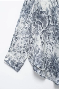 Detail view of snakeskin print shirt cuffs and curved hem with premium stitching