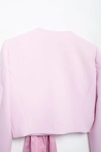 Vue détaillée du dos de la veste rose avec tissu texturé et nœud en satin élégant