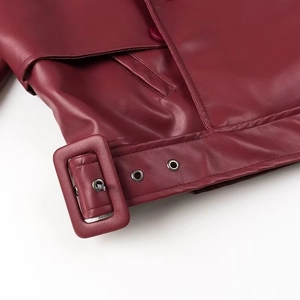 Détail de l'ourlet de la veste en cuir bordeaux avec boucle métallique et œillets de ceinture