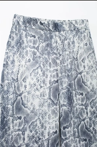Detailed macro view of gray and white snakeskin print texture on wide-leg trousers