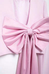 Vue détaillée du grand nœud en satin rose sur le blazer élégant pour femme