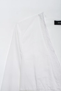 Détail du chemisier blanc à col en V avec bordure en dentelle fine et texture de tissu