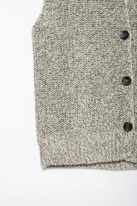 Detailed macro view of mixed beige knit fabric with chunky black buttons and ribbed hem