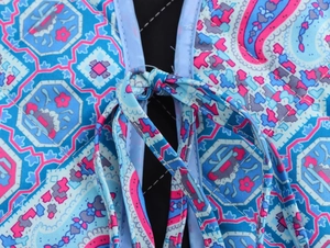 Détail d'un gilet en coton matelassé avec imprimé paisley et fermeture à nouer devant