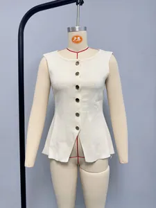 Détail du gilet en maille crème avec de gros boutons dorés et un ourlet à basque